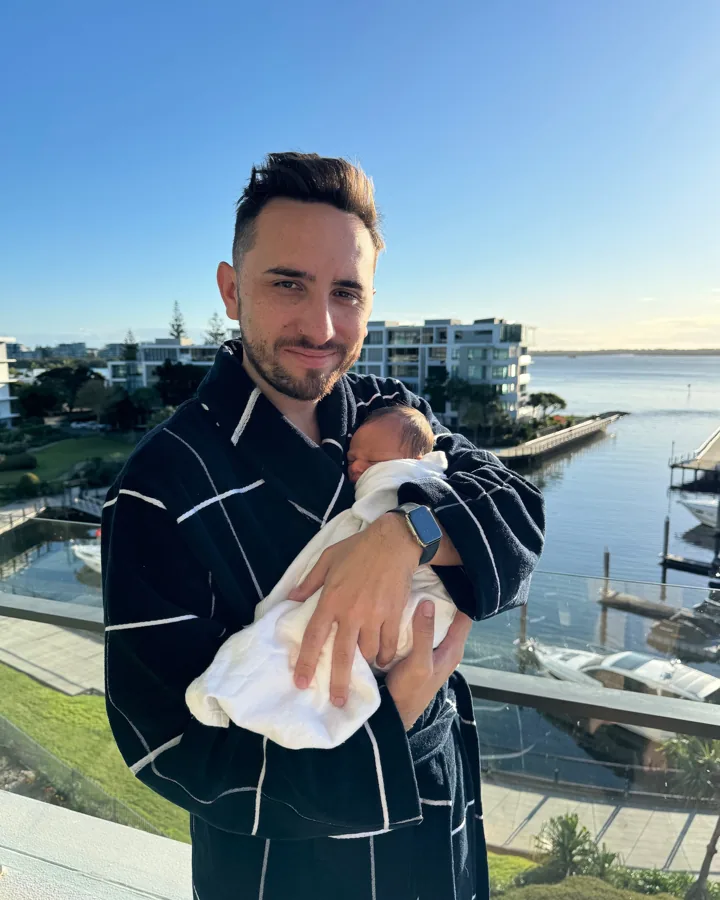 Lewis holding his newborn son Lex on the balcony, 2024
